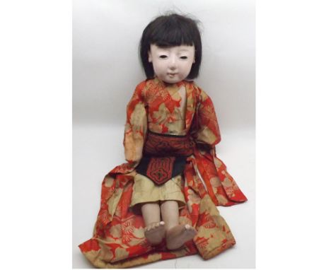 An early 20th Century Japanese Ichimatu doll, moulded composition head with fixed glass eyes, painted brows and lips, black w