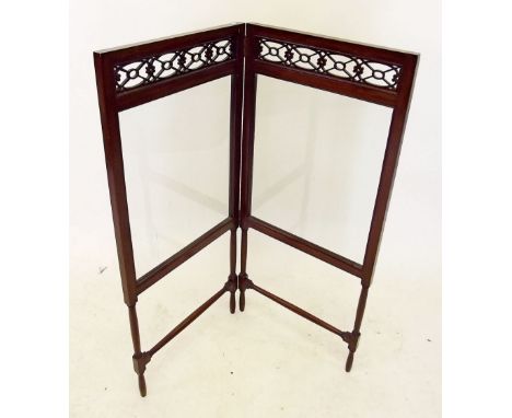 An Edwardian mahogany folding fire screen with pierced mahogany frieze and glass panels 