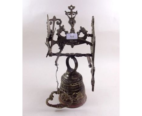 A brass bell on bracket with ornate decoration 