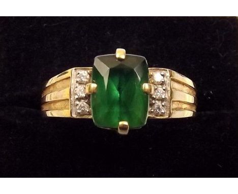 An 18ct gold ring set green stone on diamond set shoulders 