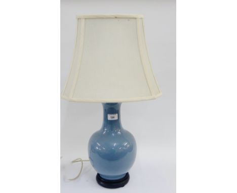 Pale blue glazed ceramic lamp base and shade with an ebonised wooden stand, 35cm high, excluding shade