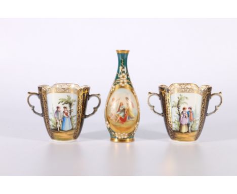 Two Dresden Helena Wolfsohn two-handled chocolate cups with Watteau style scenes and cobalt and gilt panels, 'D' crown mark t