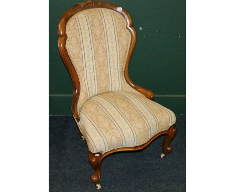 Victorian mahogany nursing chair with carved top rail raised on cabriole supports with brass and ceramic castors, 90 cm. 