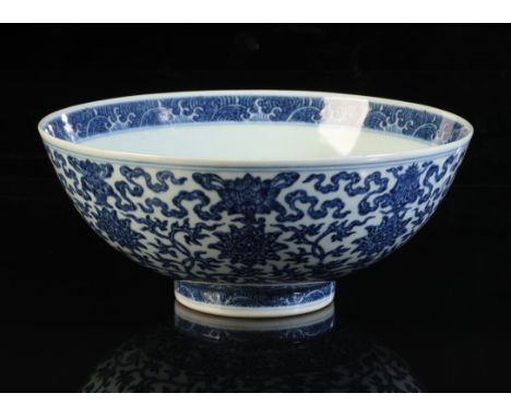 A CHINESE BLUE AND WHITE BOWL with heaped and piled decoration of lotus flowers and scrolls above a border of lappets and wav