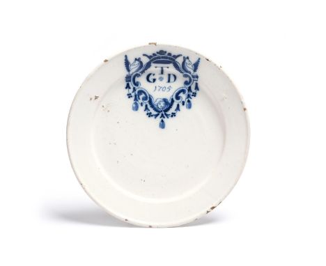 A delftware plate, dated 1705, painted in blue with the letter T over G D within a scroll cartouche flanked by winged griffin