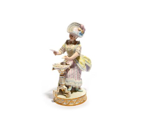 A Meissen figure of a lady, 19th century, standing beside a small tripod table with a fan of cards in her hands, wearing a pl