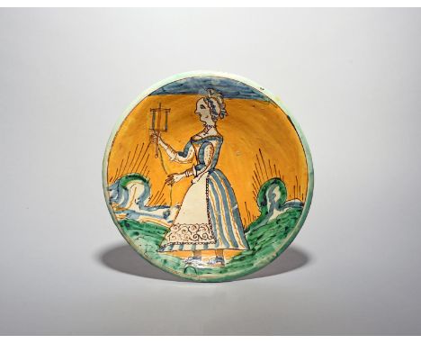 A rare Montelupo maiolica charger, late 17th century, painted with a woman standing and winding yarn from a drop spindle, res