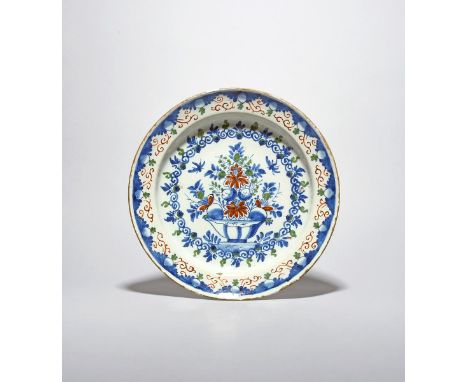 A Vauxhall delftware plate, c.1710-20, painted in blue, red and green with a basket of fruit and flowers within formal scroll