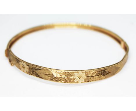 An engraved bangle marked '375', diam. 60mm, wt. 5.50g.  Condition - a number of dings and slightly bent, general wear.