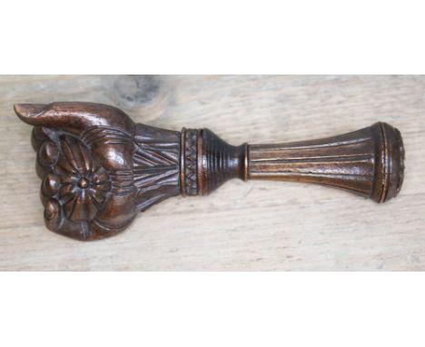 A treen nut cracker, 19th century, modelled as a hand clenching a nut, marked 'Flegere', length 15.5cm.  