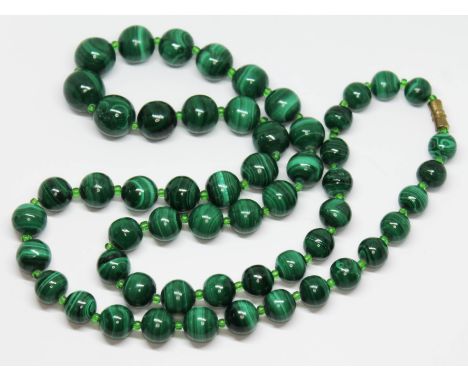 A vintage graduated single strand of malachite beads, ranging in diameter from 10mm to 15mm, interspersed with transparent li
