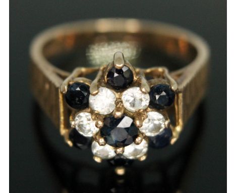 A colourless and dark blue sapphire cluster ring, the cluster head measuring approx. 13mm x 11mm, hallmarked 9ct gold band, g