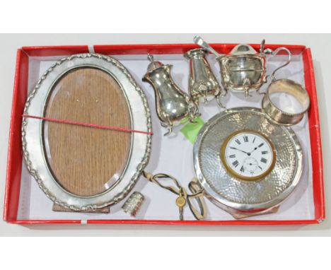 Assorted hallmarked silver comprising a photograph frame, a clock, a cruet, a serviette ring and a thimble, various dates and