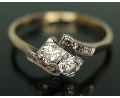 An early 20th century diamond cross over ring, the two central round brilliant cut diamonds weighing approx. 0.24 &amp; 0.26 