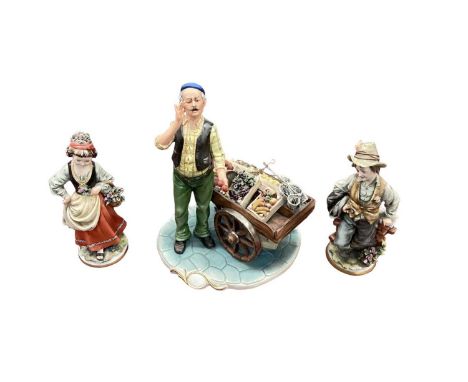 Capodimonte porcelain figure of a fruit seller with market stall, together with a pair of Capodimonte figures (3)