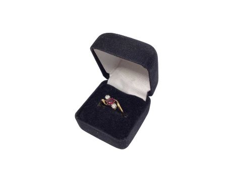 Ruby and diamond three stone cross over ring with an oval mixed cut ruby flanked by two brilliant cut diamonds in claw settin