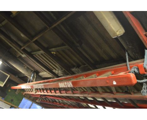 An iconic red painted wooden steeplejack ladder bearing the name 'Fred Dibnah and Sons Steeplejacks Bolton', with metal rung 