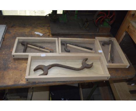 Three iron dogs and a spanner, each in display cases (4).