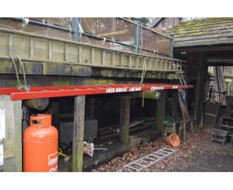 An iconic red painted wooden steeplejack ladder bearing the name 'Fred Dibnah and Sons Steeplejacks Bolton', with metal rung 