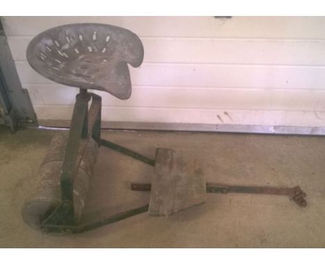 A vintage garden roller with metal seat and hitch for towing