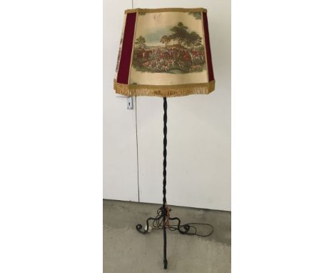 A wrought iron lampstand with shade depicting hunting scenes