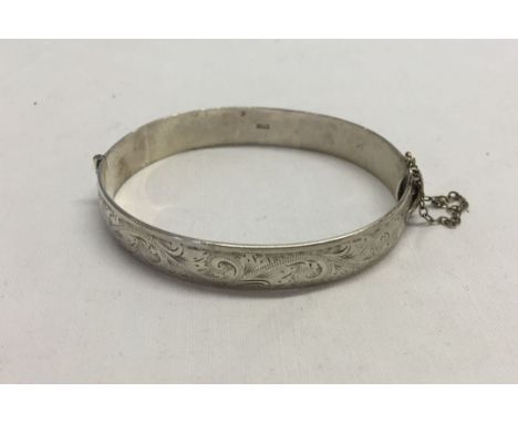 A Hallmarked silver bangle, with safety chain. Birmingham 1963. Approx 24.9g