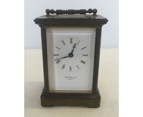 H.J. Cooper brass carriage clock with bevelled edge glass and key. Approx 11cm high excluding handle.