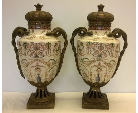 A pair of large ceramic urns on brass pedestals with brass serpent handles and brass crown.