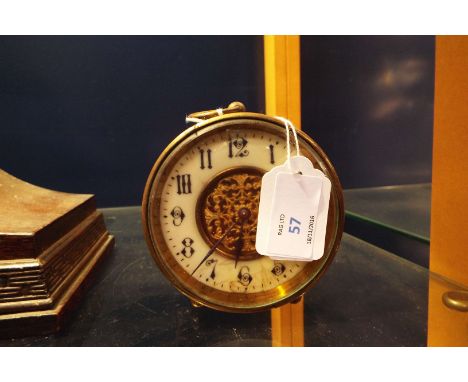 A brass cased clock with enamel dial and central filigree design  In working order