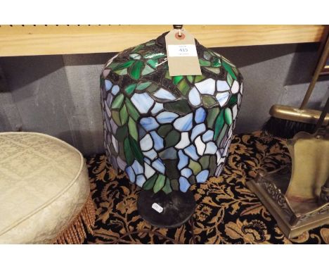 A table lamp with Tiffany style shade in blues and greens, on a shaped base