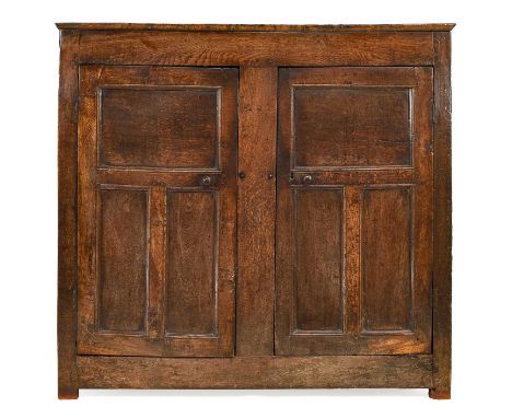 An Early 18th Century Joined Oak Cupboard, the boarded top above two cupboard doors with fielded panels enclosing additional 