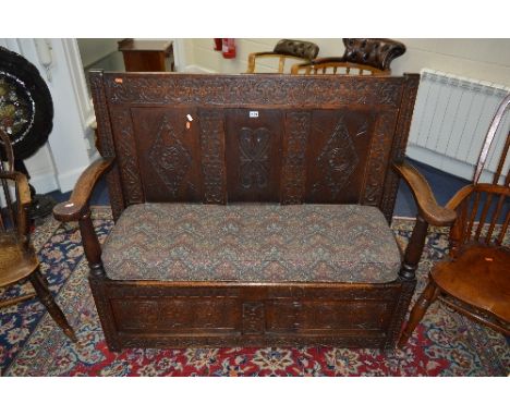 A GEORGIAN CARVED OAK HALL SETTLE, with triple panel back and hinged storage compartment, approximate size width 130cm x heig