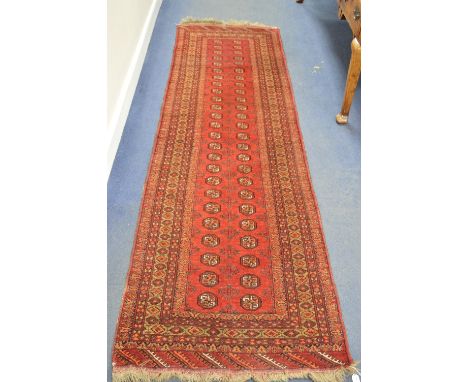 AN EARLY 20TH CENTURY CAUCASION STYLE RED GROUND CARPET RUNNER, multi strap border with central panel of geometric patterns, 