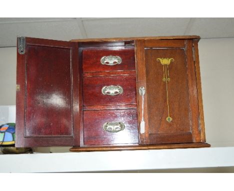 AN ARTS AND CRAFTS STYLE MAHOGANY SMOKER'S CABINET, printed decoration to the doors, fitted with three drawers and shelf