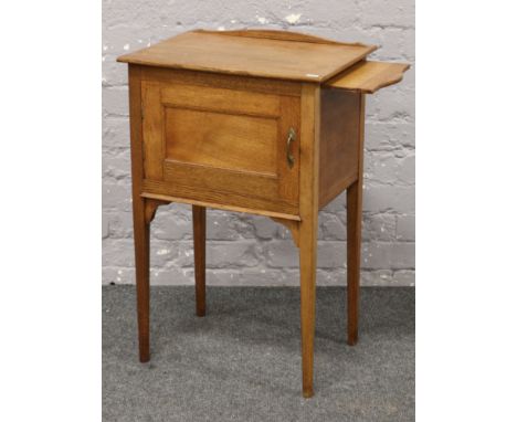 A light oak pot cupboard raised on tapering square supports.