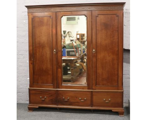 A George V plum pudding mahogany triple wardrobe with mirrored centre and fitted press to left hand side, ornamented with bli