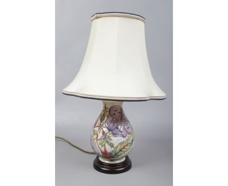 A Moorcroft pottery table lamp cream ground decorated with flowers and leaves.