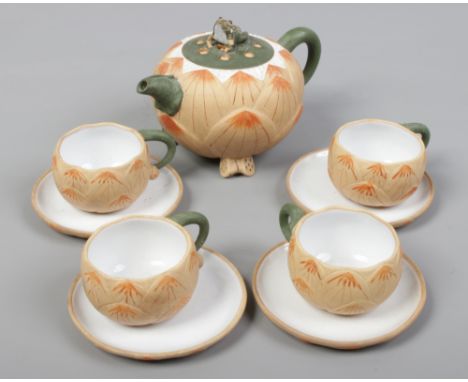 A Japanese coloured stoneware teapot and four cups and saucers, each formed as a lily, the teapot finial formed as a frog, se