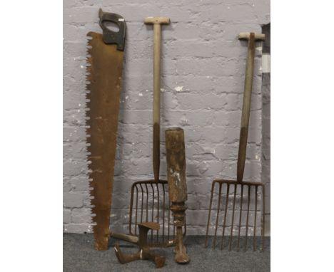 A selection of hobbing feet, two man wood saw, hay fork and one similar.