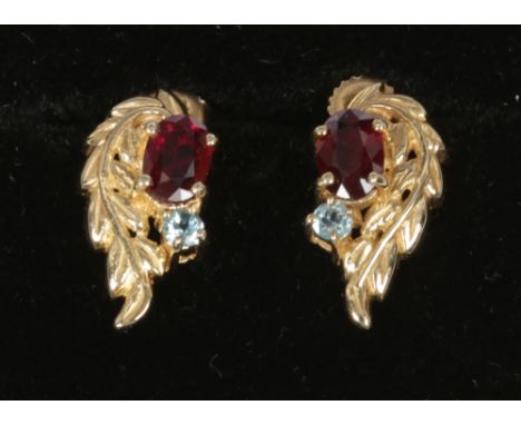 A pair of 9ct gold ruby and blue topaz foliate scroll ear studs.