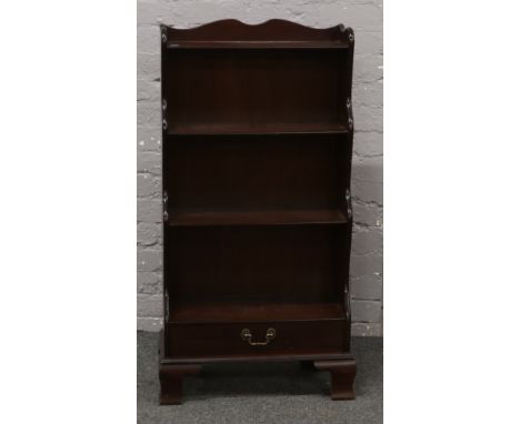 A mahogany waterfall bookcase with single drawer and raised on ogee bracket feet.