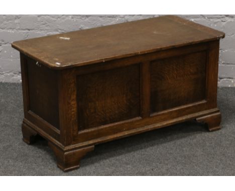 A panelled oak blanket box, raised on bracket feet.