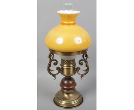 A brass effect table lamp in the form of an oil lamp with amber and opaque glass shade.