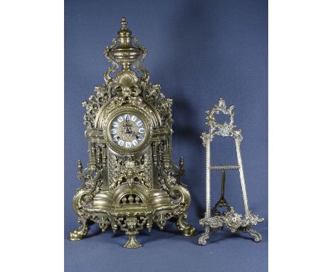 ROCOCO BRASS MANTEL CLOCK and an easel frame, the clock being antique style cast in pierced and applied decorations with urn 