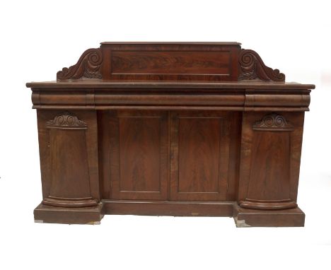 A William IV mahogany breakfront sideboard, with flame panelled back with carved scroll ends, three oak lined frieze drawers 