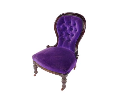 A Victorian mahogany balloon back nursing chair, upholstered in button back purple draylon and overstuffed seat cover, raised