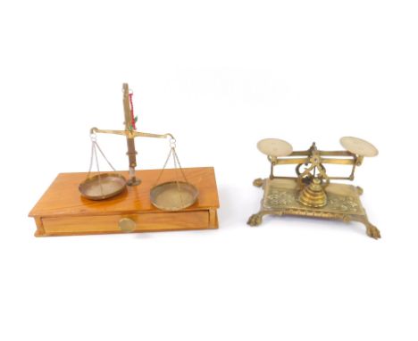 A pair of Victorian brass scales, raised on a rectangular base embossed with foliate decoration, on lion's paw feet, with fou