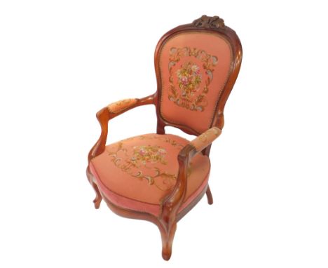 A Victorian mahogany lady's spoon back armchair, with foliate carved crest rail, wool work floral button back and overstuffed