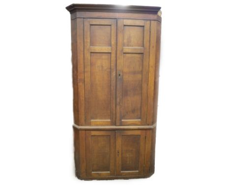 A George III oak standing corner cupboard, with moulded cornice, over two double moulded panel doors and two further to the b