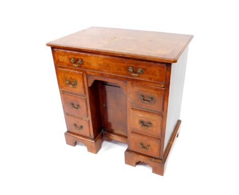 A George II walnut and feather crossbanded kneehole desk, with a quarter veneered top, over one long and six short drawers, f